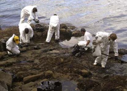 Unos operarios limpian la playa de A Punta, que tuvo que ser cerrada al baño por el vertido de fuel.