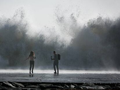 Una pareja intenta hacer una foto en la playa de Barcelona.