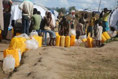 Los refugiados hacen cola para coger agua.