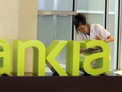 Una operaria limpia el logo de Bankia. 