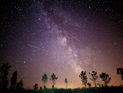 Un joven observa el cielo desde el concello coruñés de Monfero, con la Vía Láctea sobre su cabeza y con varios meteoros de las conocidas como Perseidas.