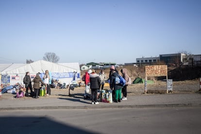 Unos refugiados ucranios que acaban de llegar a Medyka (Polonia) esperan un autobús que les lleve a la estación de tren de Przemyśl o al Centro Comercial Tesko, convertido en refugio de primera acogida. En estos lugares podrán subirse a un tren gratuito, un autobús o un coche rumbo a otras ciudades de Europa.