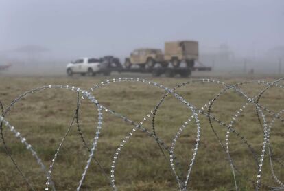 Tras un alambrado de la frontera en Texas que separa México de EE UU, se ven varios vehículos del ejército estadounidese en la mañana nublada de este lunes.