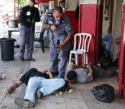 Un policía israelí vigila a un detenido (derecha) junto al cadáver de otro palestino ayer en Jerusalén.