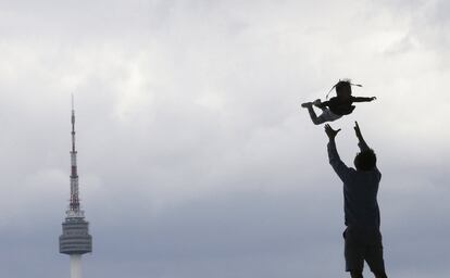 Silueta de un hombre lanzando a su hija por el aire, frente al Museo Nacional de Corea, en Seúl (Corea del Sur).