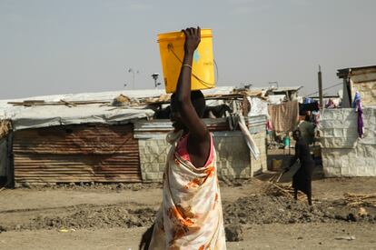 Una mujer carga con un cubo de agua en la cabeza en un campo de desplazados en la localidad de Malakal, en Sudán del Sur, en mayo de 2019.