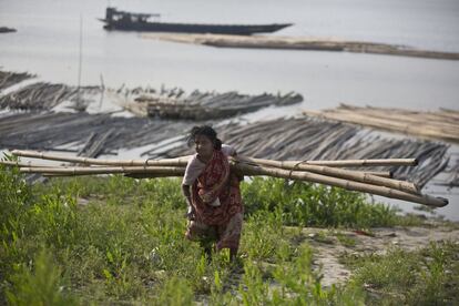 Geeta Das, uma idosa indiana, carrega bambus próximo de um mercado junto ao rio Brahmaputra em Gauhati, (Índia), em 7 de março.