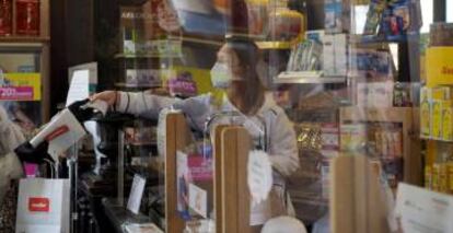 Una persona es atendida por una trabajadora de una farmacia.