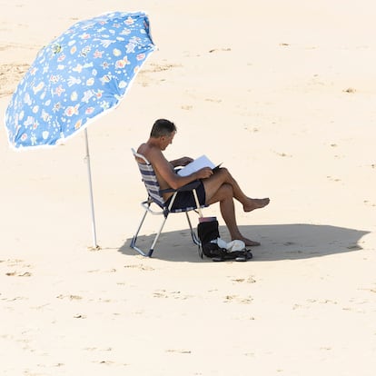 SAN SEBASTIÁN, 07/08/2025.- Un hombre lee bajo su sombrilla en la orilla de la playa de La Concha de San Sebastián este jueves, donde se esperan temperaturas superiores a 30ºC. Los cielos en Euskadi se presentan hoy poco nubosos o despejados, con algunos intervalos de nubes altas durante la primera mitad del día y por la noche en la vertiente cantábrica. EFE/Javier Etxezarreta
