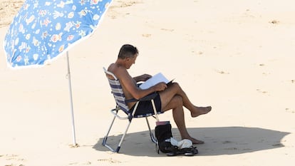 SAN SEBASTIÁN, 07/08/2025.- Un hombre lee bajo su sombrilla en la orilla de la playa de La Concha de San Sebastián este jueves, donde se esperan temperaturas superiores a 30ºC. Los cielos en Euskadi se presentan hoy poco nubosos o despejados, con algunos intervalos de nubes altas durante la primera mitad del día y por la noche en la vertiente cantábrica. EFE/Javier Etxezarreta
