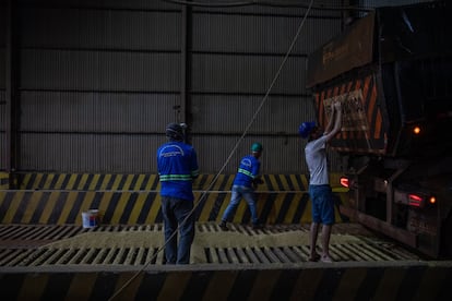 Varios operarios descargan un camión de soja, recién llegado de una hacienda. Una vez pesado y procesado, será cargado en otro vehículo para ser transportado hasta un puerto. Los locales se felicitan de que el presidente Bolsonaro haya asfaltado los 175 kilómetros que faltaban para que los 900 kilómetros de la carretera BR-163 sea transitables a lo largo de todo el año.