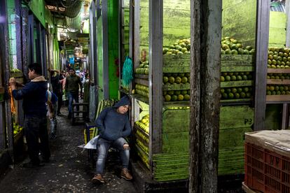 Un comerciante duerme en su puesto de fruta al amanecer.