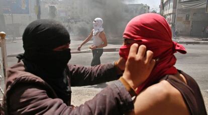 Un manifestante palestino coloca la camiseta que cubre la cara de otro manifestante durante enfrentamientos con fuerzas de seguridad israelíes en Hebrón, Cisjordania.