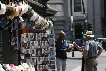 Una pareja compra sombreros para resguardarse del sol en un quiosco de Madrid.