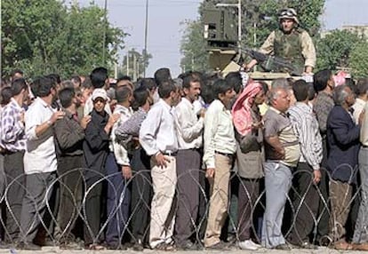 Un soldado de EE UU vigila a trabajadores de la North Oil, que esperan el cobro de sus salarios en Kirkuk.