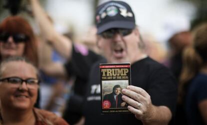 Eleitor de Trump mostra livro durante evento de campanha.