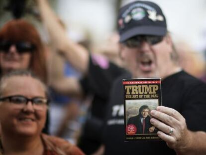 Eleitor de Trump mostra livro durante evento de campanha.