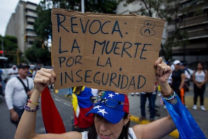 Una mujer sostiene un cartel junto a un grupo de personas que participan en la marcha de la oposición en Caracas.