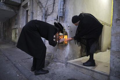Un hombre y una mujer judíos ultraortodoxos encienden velas en la segunda noche de la fiesta judía de Janucá, en el barrio ultraortodoxo de Mea Shearim de Jerusalén.