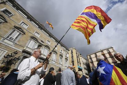 Un hombre ondea una bandera catalana y una republicana junto a otro hombre que lleva una estelada como capa durante la concentración en la plaza de Sant Jaume. 