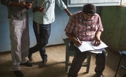 Un profesor corrige trabajos en presencia de sus alumnos.