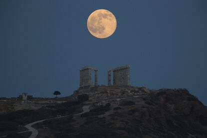 La luna llena se eleva detrás del templo de Poseidón en Atenas, Grecia.