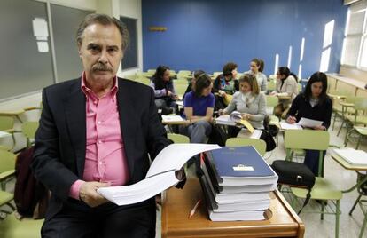 Eduardo Jevremovitch, director de la academia Magister de Madrid, posa con los temarios que hay que cambiar en un aula con alumnos.