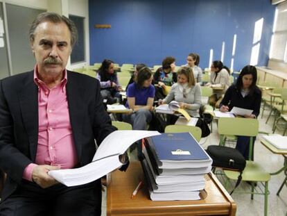 Eduardo Jevremovitch, director de la academia Magister de Madrid, posa con los temarios que hay que cambiar en un aula con alumnos.