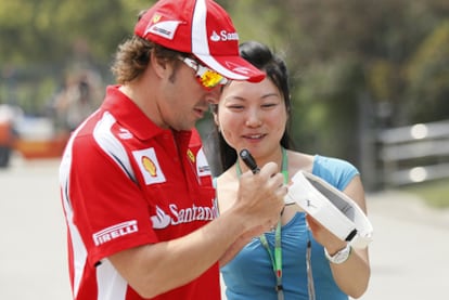 El piloto de Ferrari Fernando Alonso firma un autógrafo a una aficionada.