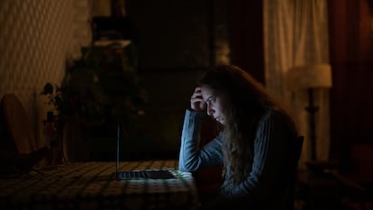 Una mujer lee en su computadora desde su hogar.