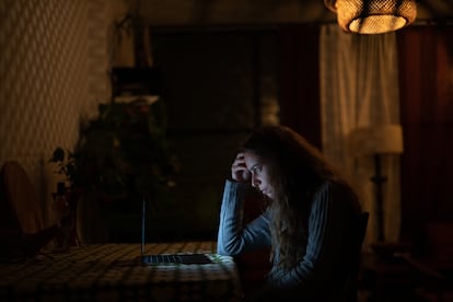 Una mujer lee en su computadora desde su hogar.