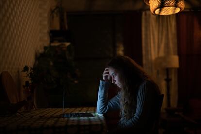 Una mujer lee en su computadora desde su hogar.