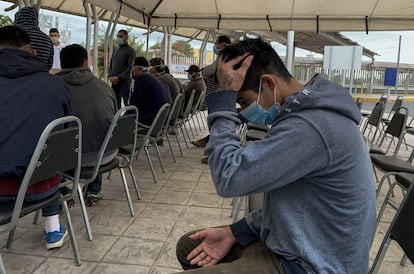 Sentado y con la cara cubierta con un tapabocas, un hombre que fue detenido cuando intentaba cruzar la frontera escucha sus derechos en un centro de migración en Tamaulipas.