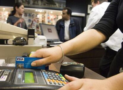 Una dependienta cobra a un cliente en una tienda con una tarjeta Visa.