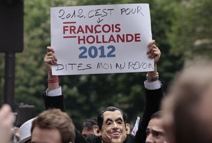 Un simpatizante del candidato socialista François Hollande, portando una máscara de Nicolas Sarkozy, muestra un cartel en el que se lee "2012 es para François Hollande, dime adiós", en una concentración a las afueras de la sede del PS francés.