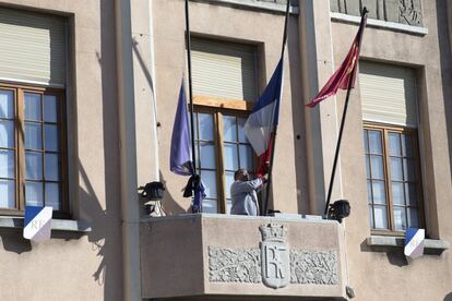 Un hombre coloca la bandera francesa a media asta en el ayuntamiento de Trèbes tras el secuestro que ha causado al menos tres muertos en la localidad francesa. 