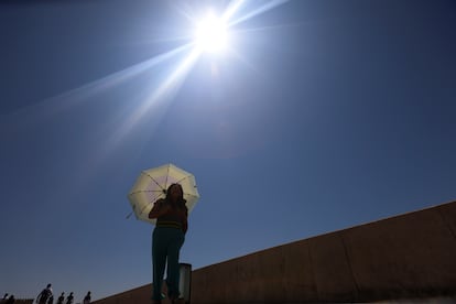 Una mujer se protege del sol con una sombrilla mientras camina por el centro de Córdoba, este martes. 
