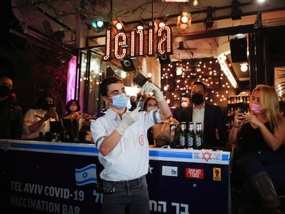 Un sanitario prepara una inyección ante un bar donde se ofrece una bebida gratis a quienes se vacunen contra la covid, el jueves en Tel Aviv.