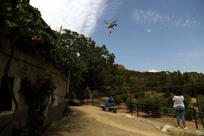 Los vecinos de Moropeche observan un helicóptero que participa en las labores de extinción del fuego.