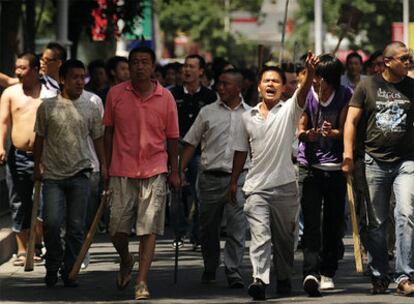 Un grupo de chinos de la etnia han patrulla con palos por las calles de Urumqi.