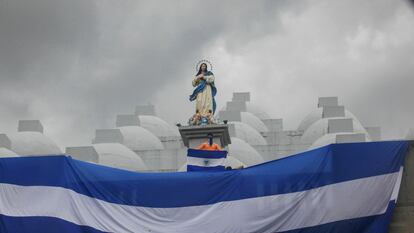 A young man holds a Nicaraguan flag on the rooftop of a cathedral during a protest.