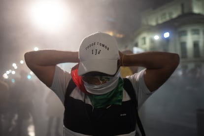 Una persona se cubre del humo de un extintor, expulsado durante un choque entre manifestantes y policías.