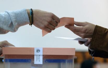 Una mujer entrega sus sobres en una mesa electoral.