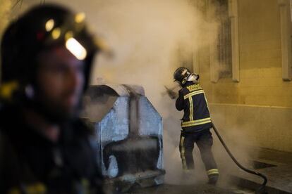 Dos bombers apagant un contenidor a Gràcia