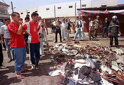 Un grupo de personas mira parte de los destrozos provocados por la bomba de ayer en un mercado argelino.