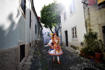 Hasta la madrugada los lisboetas se quedan a bailar en los 'bailaricos' y a comer las tradicionales sardinas asadas, símbolo de la ciudad. En la imagen, una mujer con traje tradicional pasea por las calles de Alfama, donde tiene lugar el desfile.