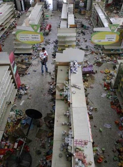 Un camarógrafo toma imágenes en un supermercado saqueado del barrio de El Pedregal, en Tegucigalpa.