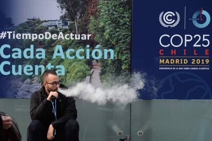 Un hombre fuma un cigarrillo electrónico en la entrada de la Cumbre del Clima que se celebra en Madrid. 