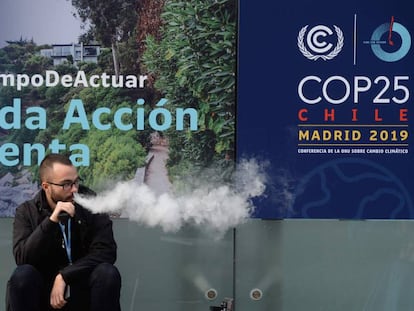 Un hombre fuma un cigarrillo electrónico en la entrada de la Cumbre del Clima que se celebra en Madrid. 