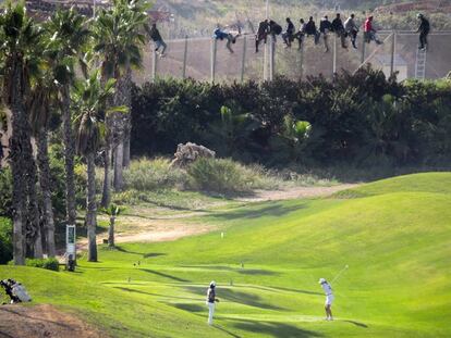 Al menos 12 inmigrantes, encaramados en la valla de Melilla frente al campo de golf situado al lado de la alambrada que separa la ciudad autonoma de Marruecos. 